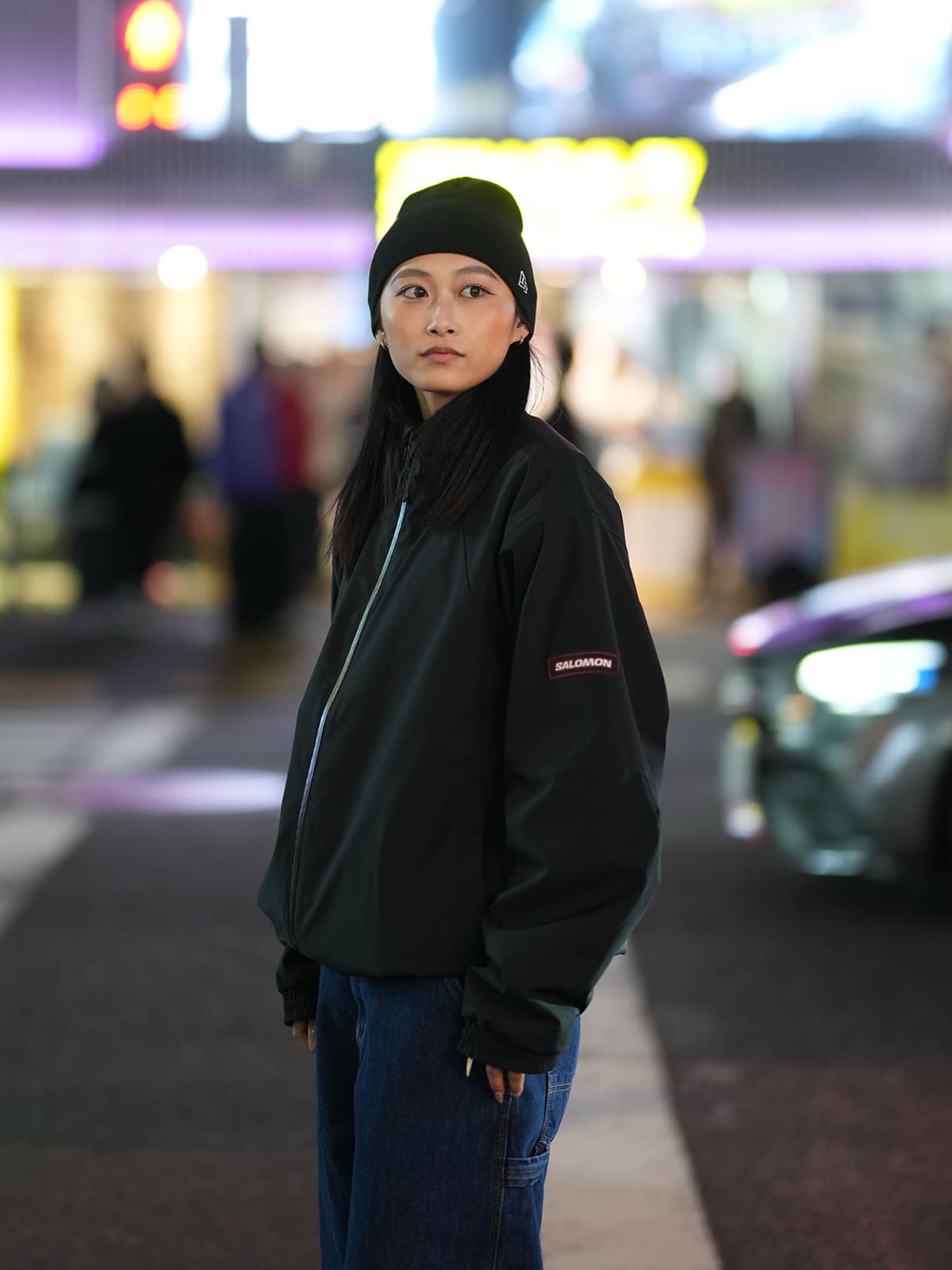 赤いジャケットにワイドパンツを合わせて街に座る女性
