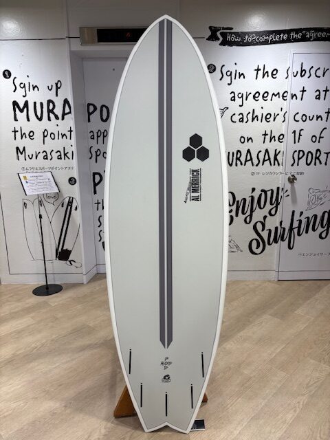 White surfboard with two dark gray stripes on display in a showroom or shop.
