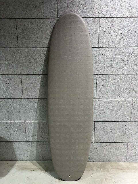 s-IMG_7409 - SHOP NEWS | ムラサキスポーツオンラインストア 通販 Gray surfboard leaning vertically against a gray tiled wall.