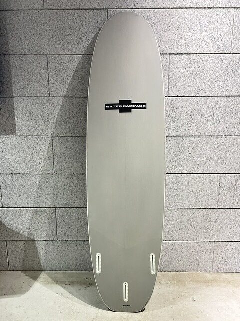 s-IMG_7412 - SHOP NEWS | ムラサキスポーツオンラインストア 通販 Grey surfboard standing upright against a tiled wall with a small black Water Rampage logo in the center.