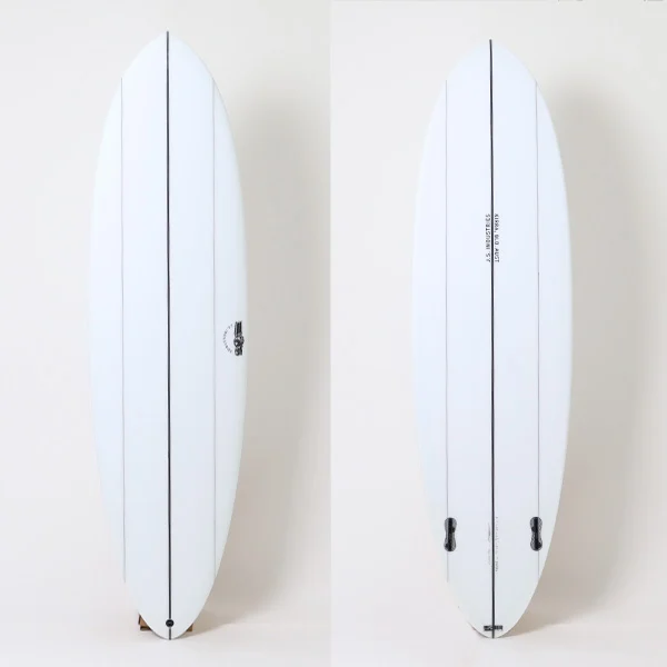 Two white surfboards standing upright against a pale background, showing central stringers and at least one fin near the tail of each board.
