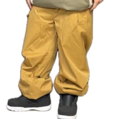 Lower body of a person wearing loose mustard-yellow pants and black sneakers with white soles.