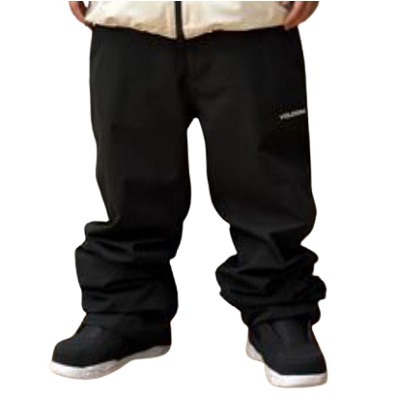 Lower half of a person wearing black loose-fit pants over black sneakers with white soles on a plain background.
