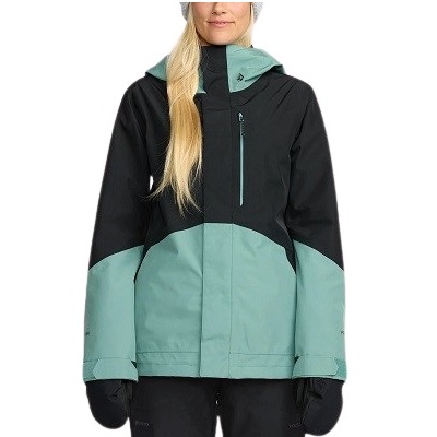 Color-block teal and black ski jacket with chest zip pocket and hood, worn by a person.