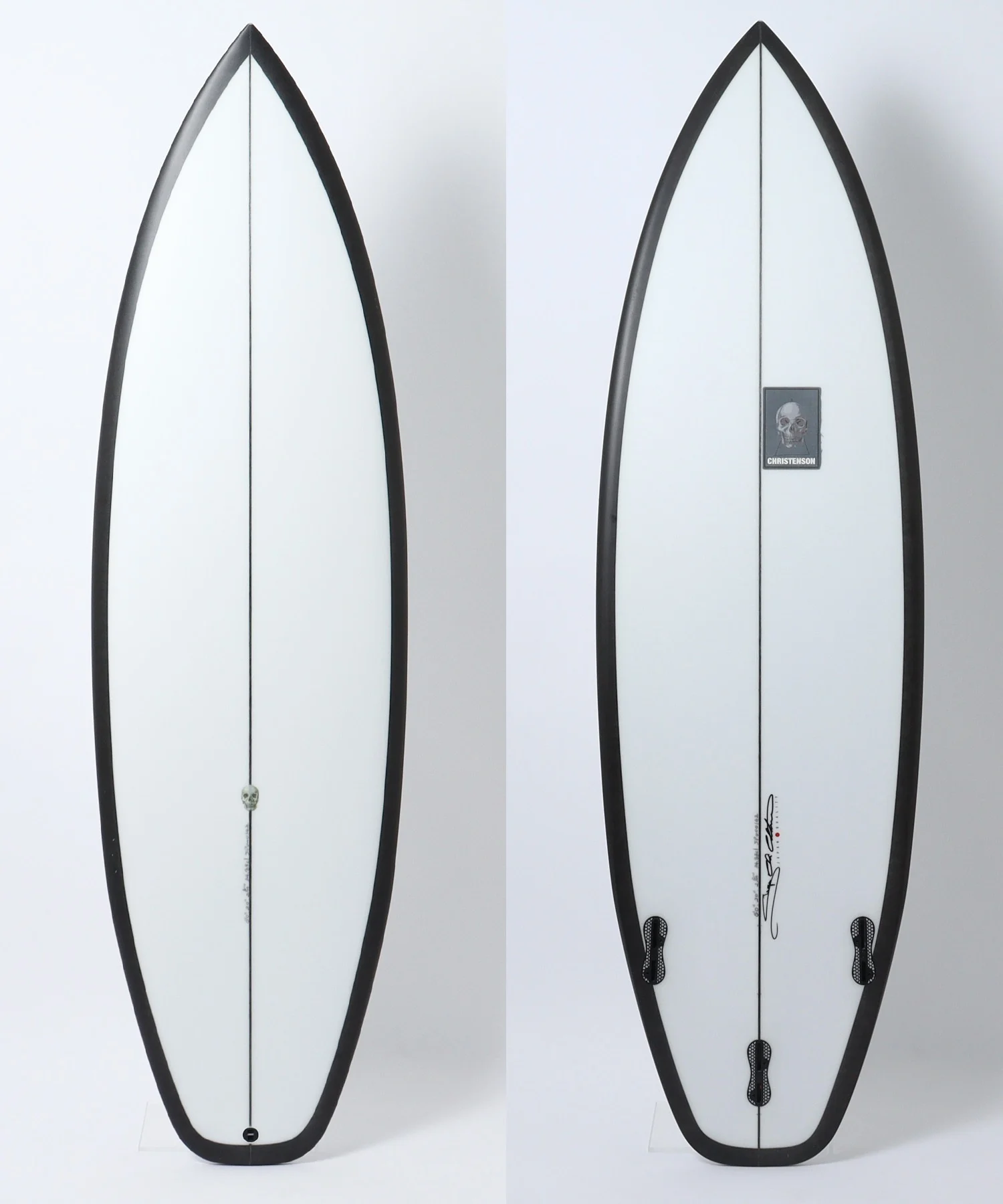 image - SHOP NEWS | ムラサキスポーツオンラインストア 通販 Two white surfboards shown side by side, highlighting the tail and deck details with black rails and a central stringer; left side features a skull sticker near the tail, right side shows signature and logo patch.