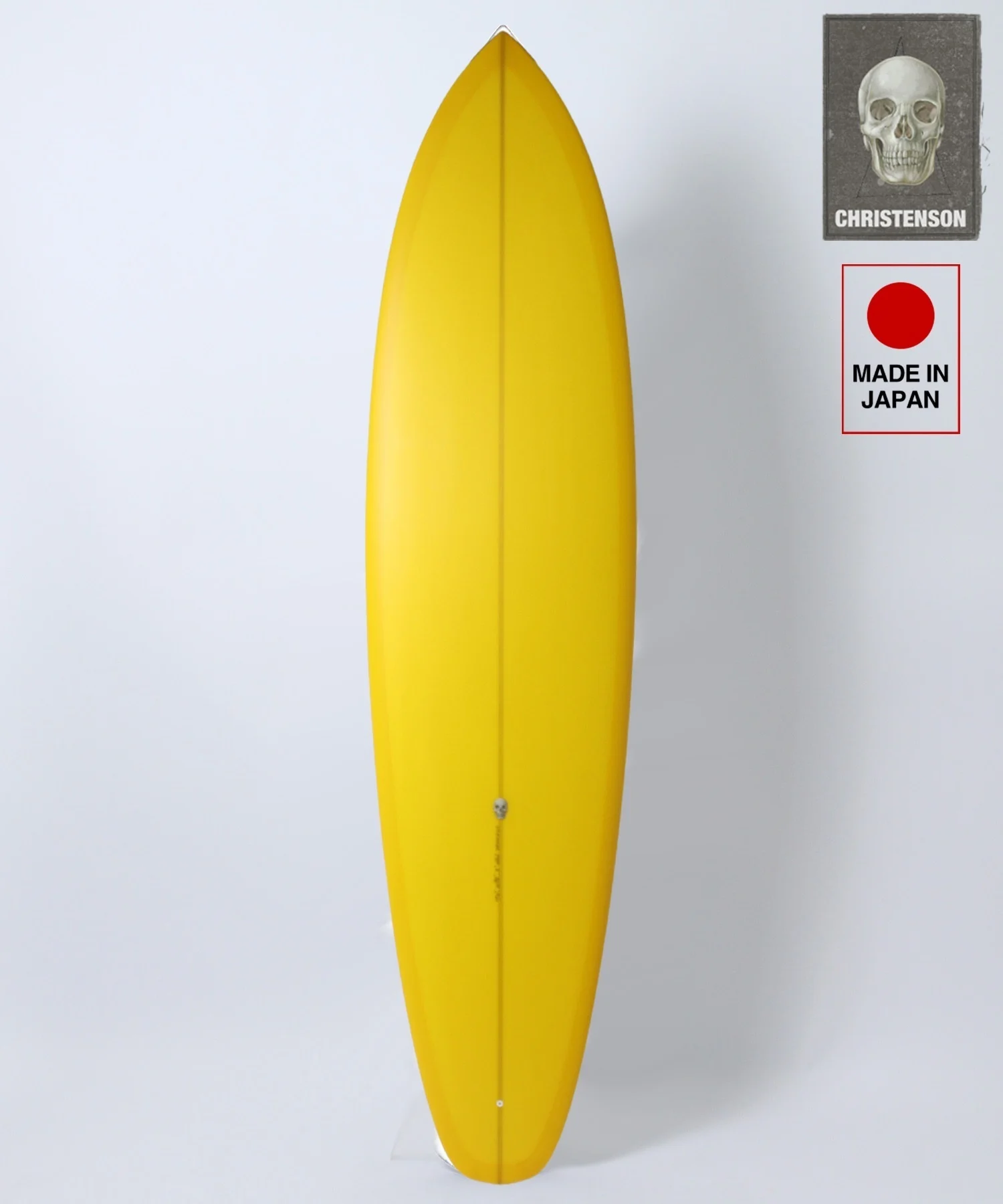 image - SHOP NEWS | ムラサキスポーツオンラインストア 通販 Yellow surfboard standing upright against a white background with two branding stickers on the right (Christenson skull card and Made in Japan label).