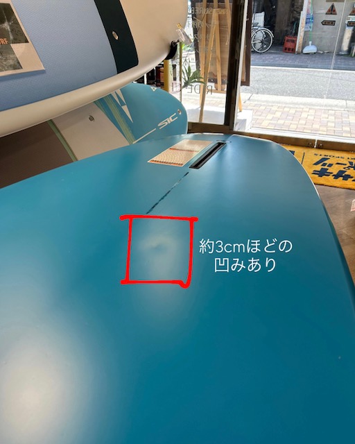 AE247361-96F1-4BAD-A9ED-A144C67A0C86 - SHOP NEWS | ムラサキスポーツオンラインストア 通販 Close-up of a blue machine surface with a small dent about 3 cm, outlined in red; there is Japanese text noting the dent on the panel.