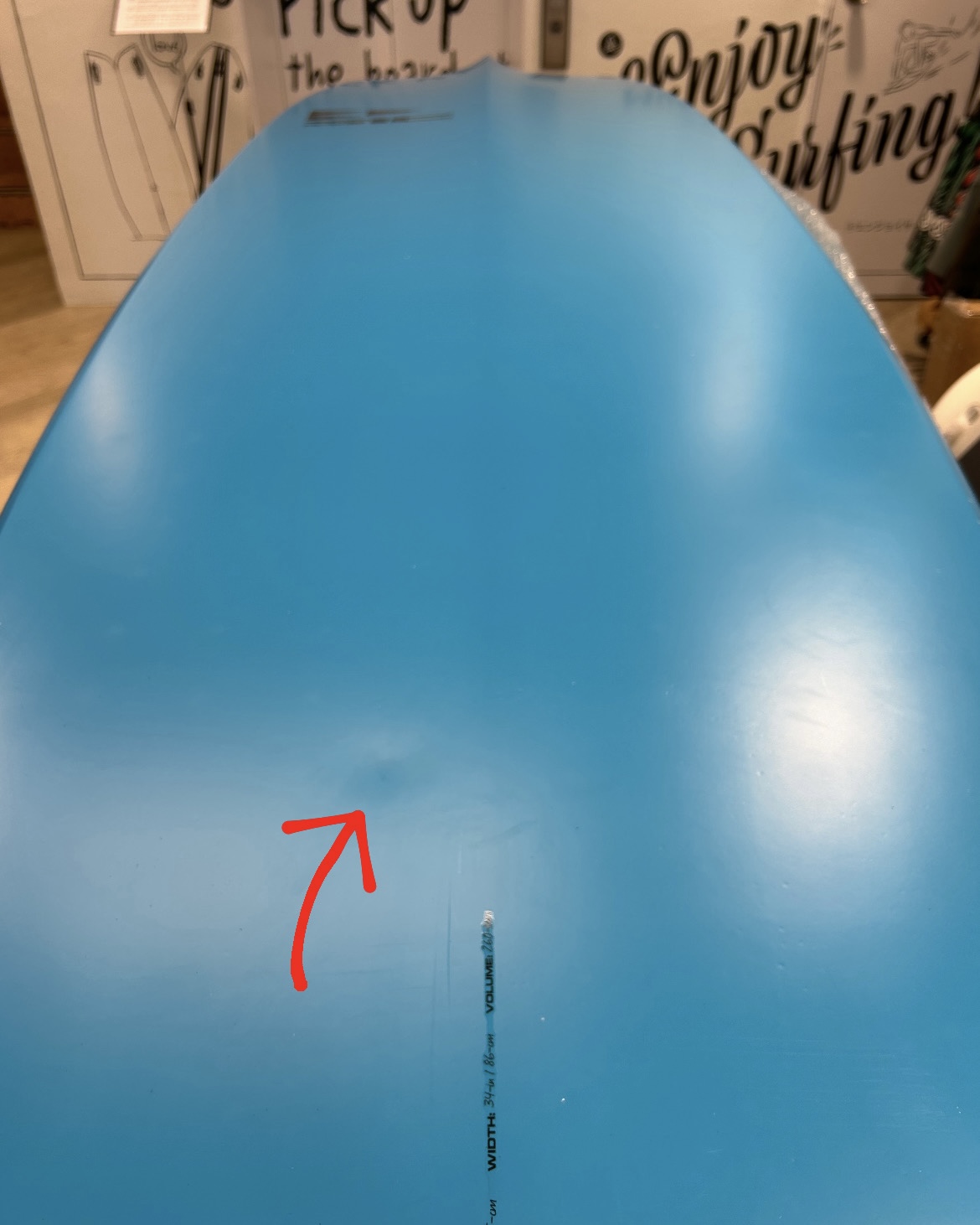 EC4CCA88-22A3-4EE8-8345-685246C2BE99 - SHOP NEWS | ムラサキスポーツオンラインストア 通販 Blue inflatable board with a red arrow indicating a small surface scratch near the center. A vertical measurement line is also visible for scale.