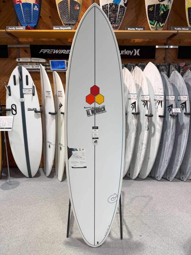 Center display surfboard with Al Merrick logo on a stand in a surf shop showroom