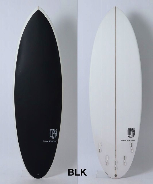 Two surfboards standing upright side by side: left one is black, right one is white with a wooden center stringer; BLK label at the bottom.