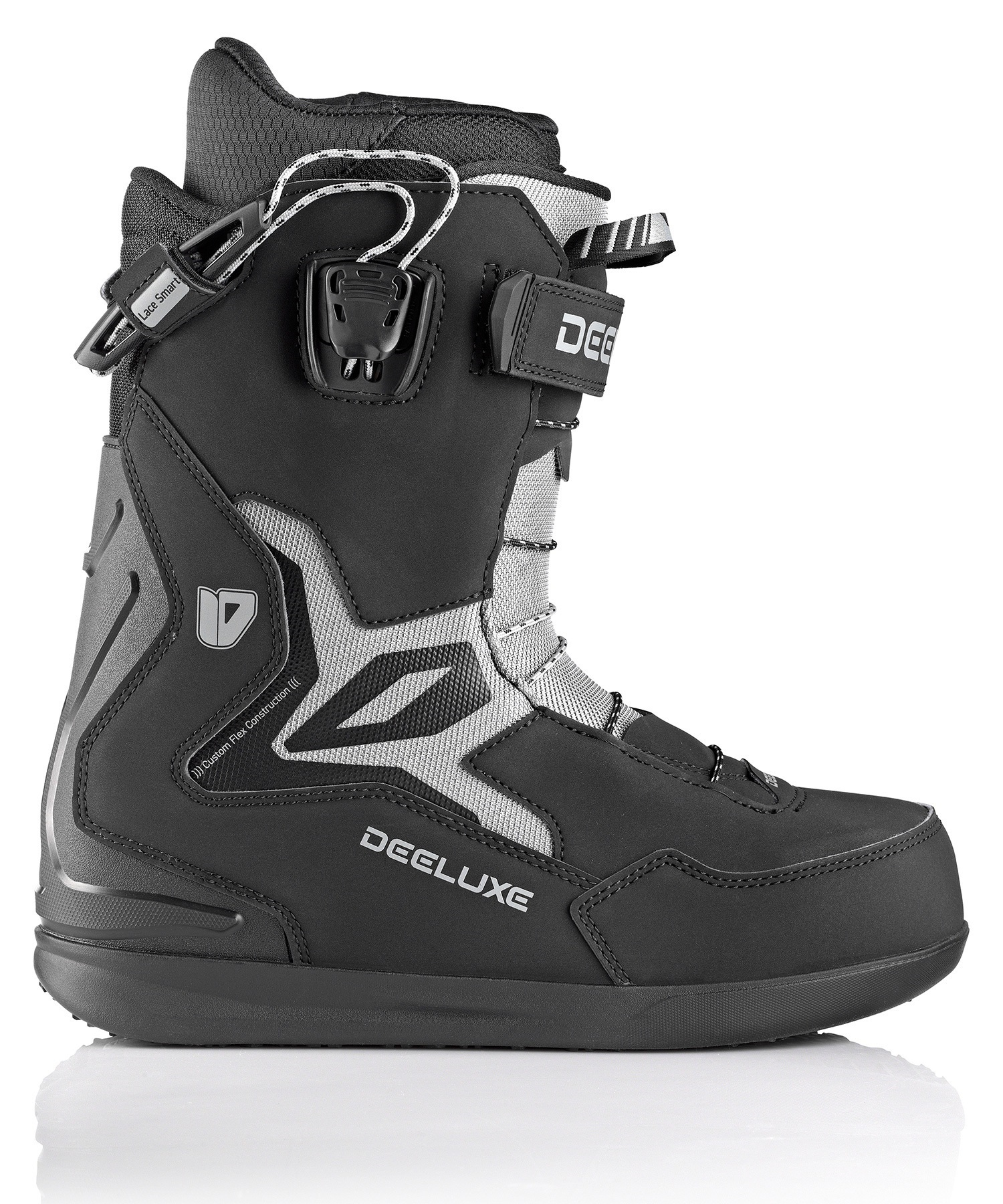 Close-up of a black and gray ski boot with buckles, straps, and laces, showing the DEG LUXE branding on the side.
