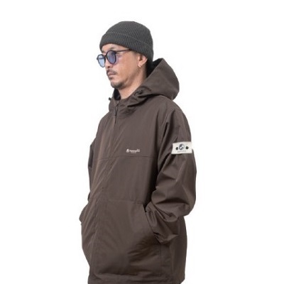 GRIND20 - SHOP NEWS | ムラサキスポーツオンラインストア 通販 Man wearing a brown hooded windbreaker with hands in pockets, gray beanie and sunglasses.