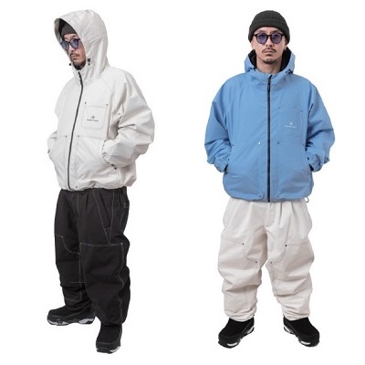 NOMADIK250 - SHOP NEWS | ムラサキスポーツオンラインストア 通販 Two men model lightweight windbreakers: white hooded jacket with black pants on the left, and blue hooded jacket with light cream pants on the right.