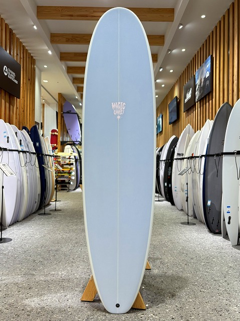 a-image4 - SHOP NEWS | ムラサキスポーツオンラインストア 通販 Light blue surfboard standing upright on display rack in a surf shop showroom.