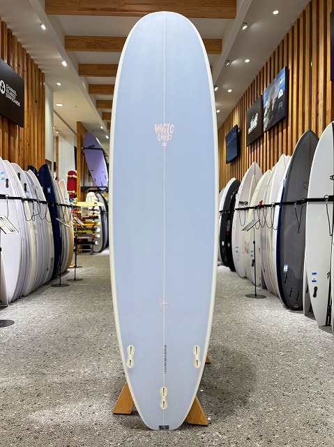 a-image5 - SHOP NEWS | ムラサキスポーツオンラインストア 通販 Light blue surfboard standing upright on a wooden display in a surf shop showroom.