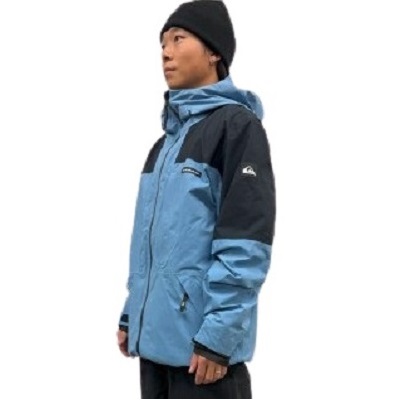 Man in a blue and navy insulated winter jacket with hood and a black knit cap, shown in profile.