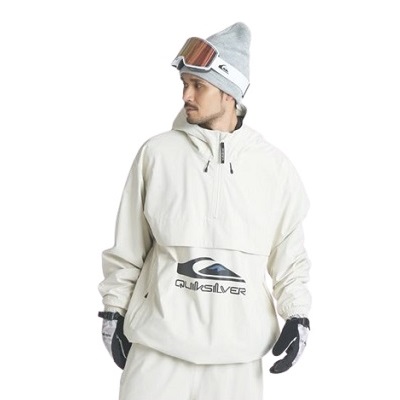 Man wearing a cream-colored snowboarding outfit with goggles and a beanie, looking to the left.