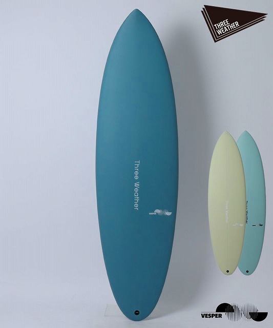 VESPER1 - SHOP NEWS | ムラサキスポーツオンラインストア 通販 Tall blue surfboard with Three Weather branding stands against a pale wall, beside two smaller pastel boards (yellow and light blue).