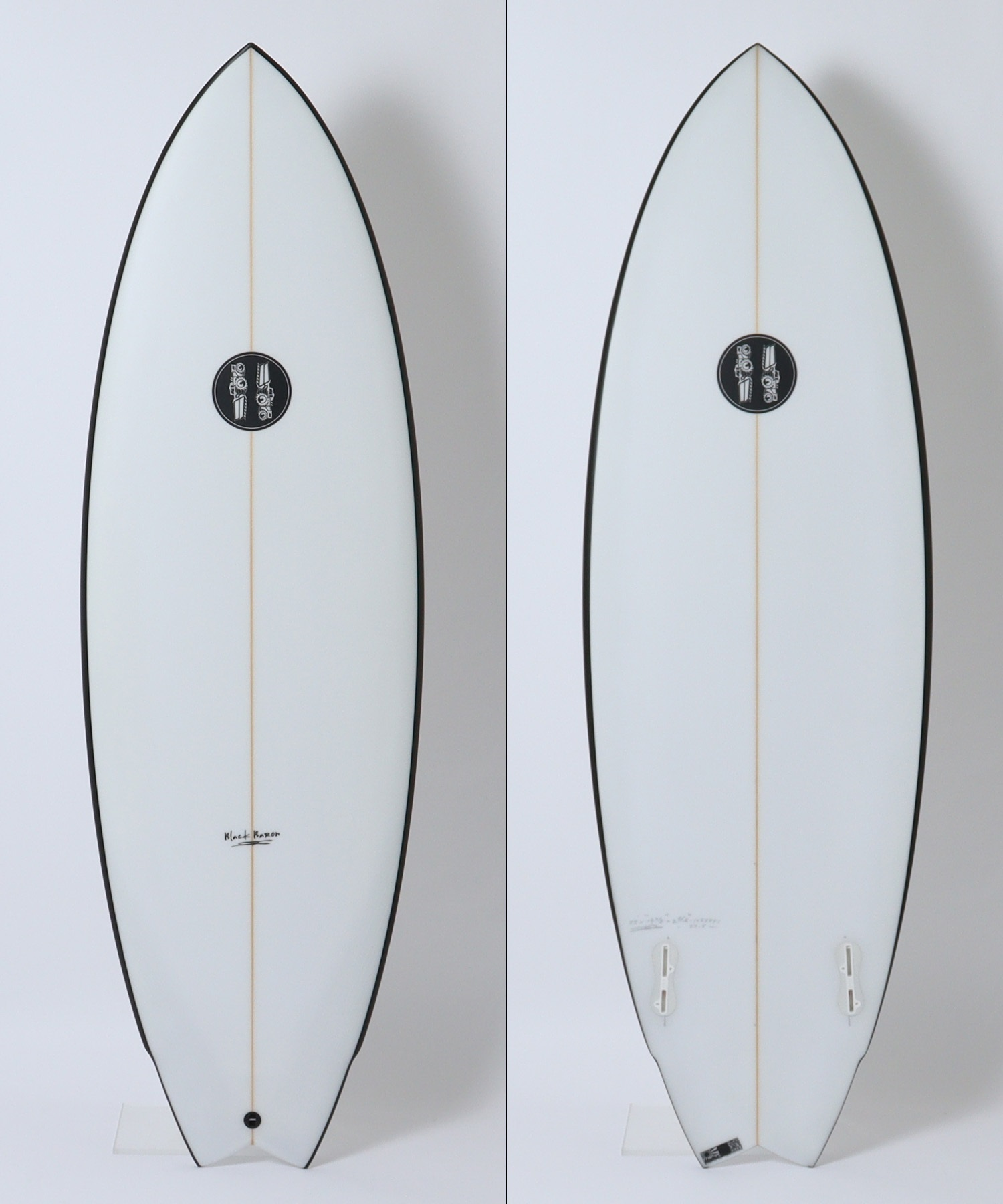 image - SHOP NEWS | ムラサキスポーツオンラインストア 通販 Front and back views of a white board with a brown-orange stringer down the center, black rails, and a circular black logo centered on the deck; photographed against a white background.